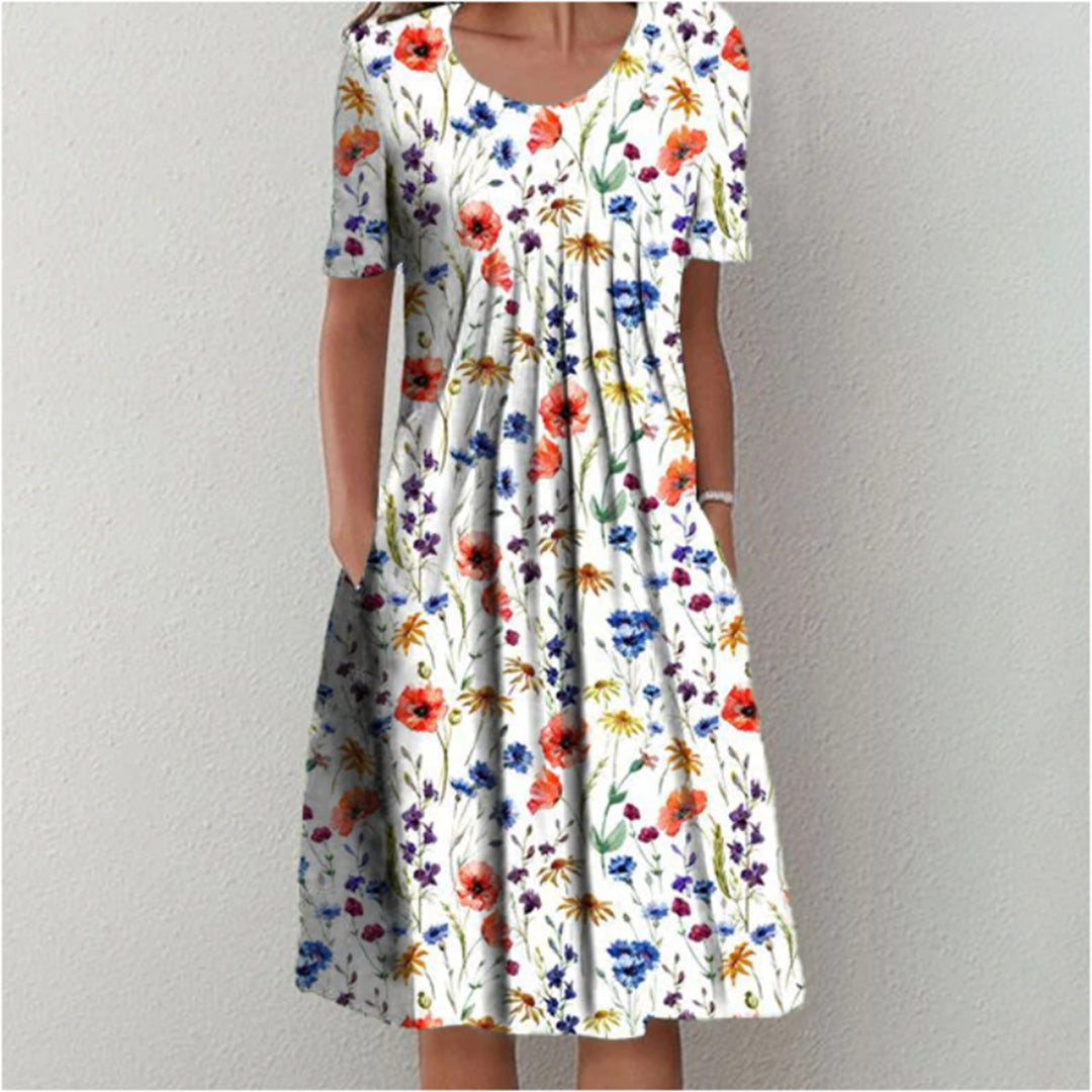 Vrouw in witte zomerjurk met kleurrijke bloemenprint, korte mouwen en ronde hals. Perfect voor casual lente- en zomermode.
