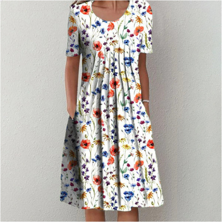 Vrouw in witte zomerjurk met kleurrijke bloemenprint, korte mouwen en ronde hals. Perfect voor casual lente- en zomermode.