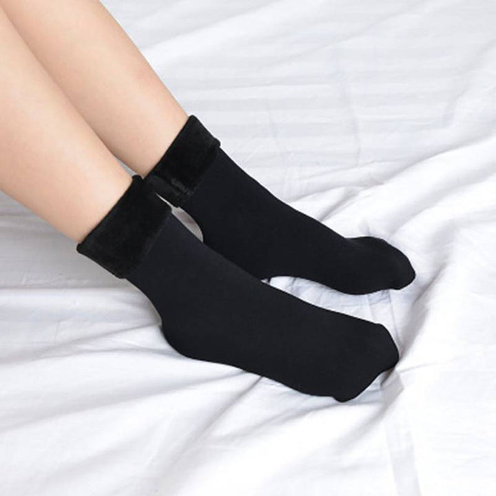 Zwarte sokken met pluche voering, gedragen op een wit laken. Comfortabele, warme sokken voor dames, ideaal voor winterse dagen.
