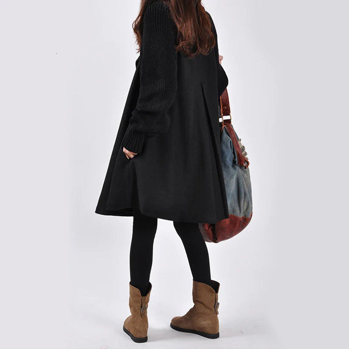 Dames winterjas zwart, lange mouwen, gecombineerd met bruine laarzen en een grote tas. Modieuze winterkleding voor vrouwen.