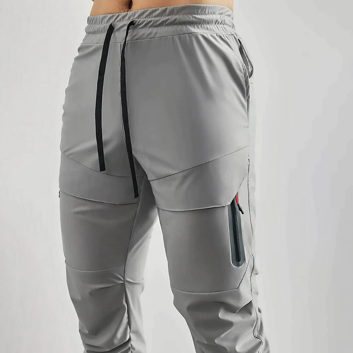 Grijze heren joggingbroek met elastische tailleband, trekkoord en zijzakken. Comfortabele sportbroek voor dagelijks gebruik en fitness.