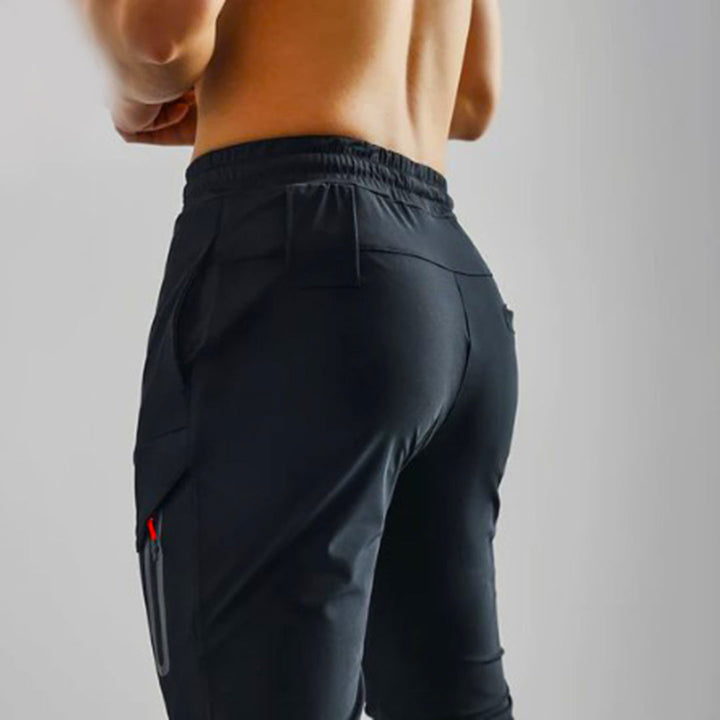 Zwarte heren joggingbroek met zakken, elastische tailleband en sportieve pasvorm. Ideaal voor fitness en casual wear. Comfortabele sportkleding.