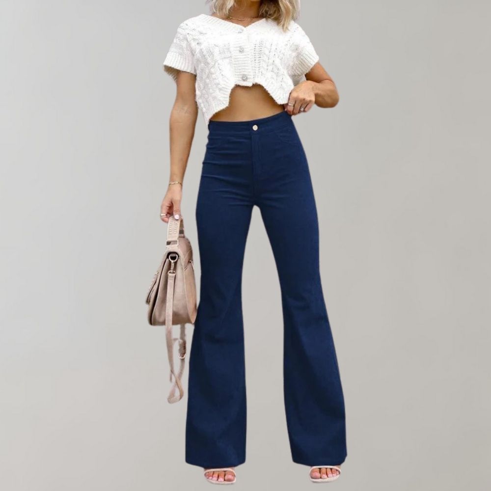 Vrouw in trendy blauwe corduroy uitlopende broek en witte crop top, met beige handtas. Modieuze dameskleding, casual stijl.