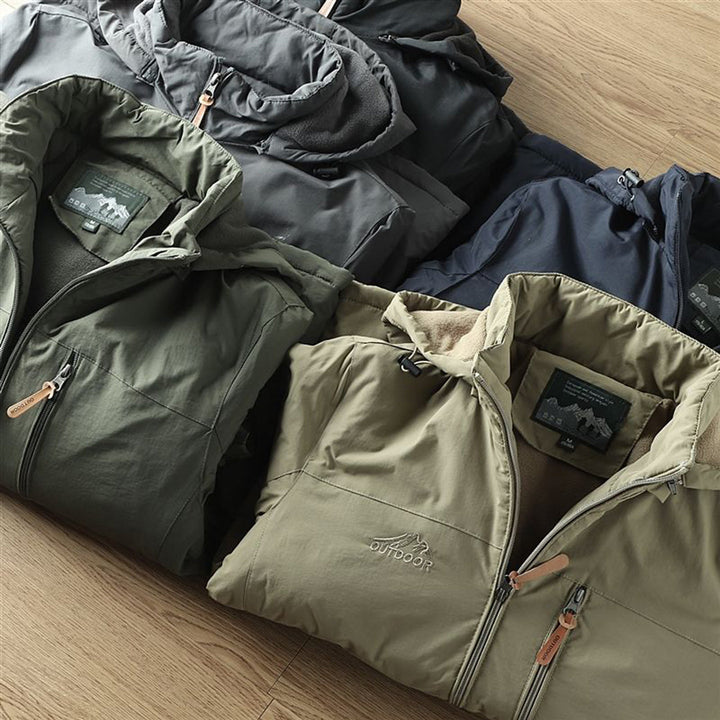 Verschillende kleuren outdoor jassen op houten vloer, met ritsen en capuchons. Ideaal voor wandelen en kamperen. Comfortabele en duurzame materialen.
