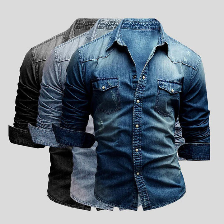 Drie denim overhemden in verschillende tinten blauw en grijs, met lange mouwen en borstzakken, op een grijze achtergrond.