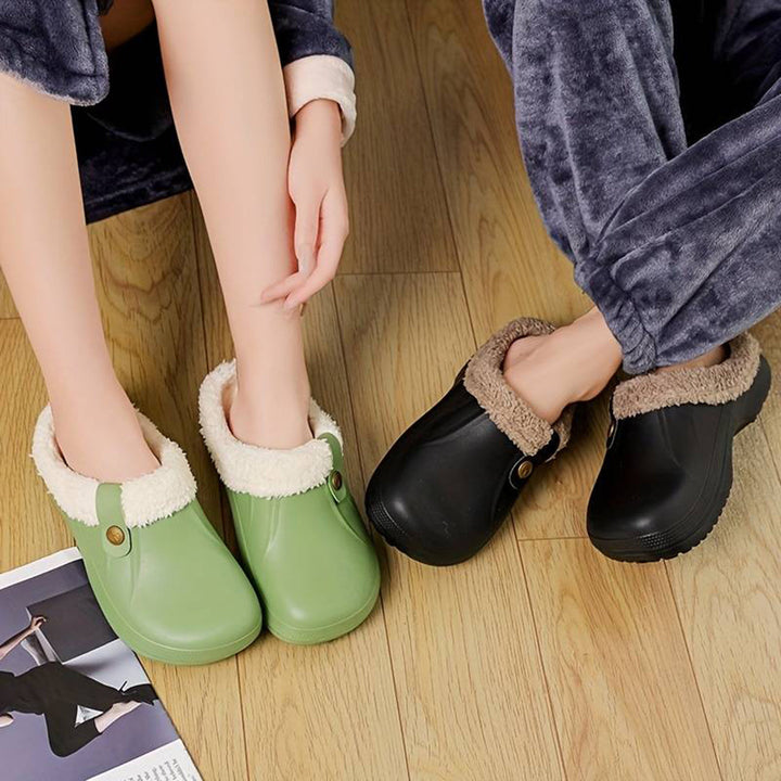 Twee paar winterklompen met bontvoering, groen en zwart, op houten vloer. Comfortabele, warme pantoffels voor binnengebruik.