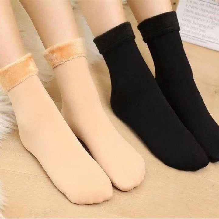 Vier paar warme, effen sokken in beige en zwart op houten vloer. Perfect voor winter, comfort en stijl. Ideaal voor dagelijks gebruik en cadeau-ideeën.