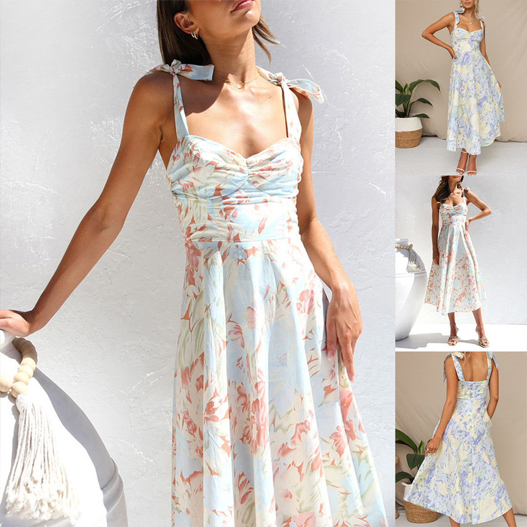 Vrouw in elegante zomerjurk met bloemenprint, pastelkleuren, strikbandjes, mouwloos, midi-lengte. Perfect voor casual en feestelijke gelegenheden.