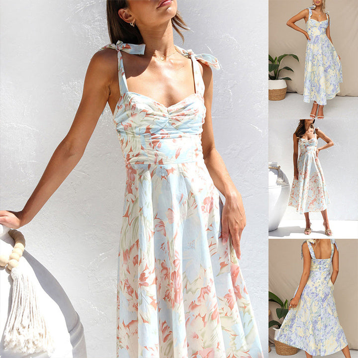 Vrouw in elegante zomerjurk met bloemenprint, pastelkleuren, strikbandjes, mouwloos, midi-lengte. Perfect voor casual en feestelijke gelegenheden.