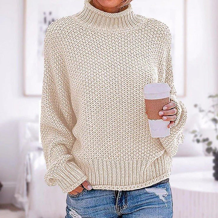 Vrouw in crèmekleurige gebreide trui met col, houdt een kartonnen koffiebeker vast. Casual mode, herfstkleding, comfortabele stijl.
