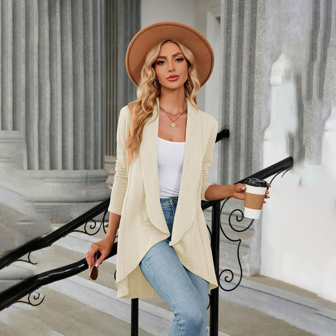 Vrouw in casual outfit met beige hoed, crèmekleurige cardigan, witte top en blauwe jeans, houdt koffiebeker vast. Stijlvolle mode, buitenlocatie.