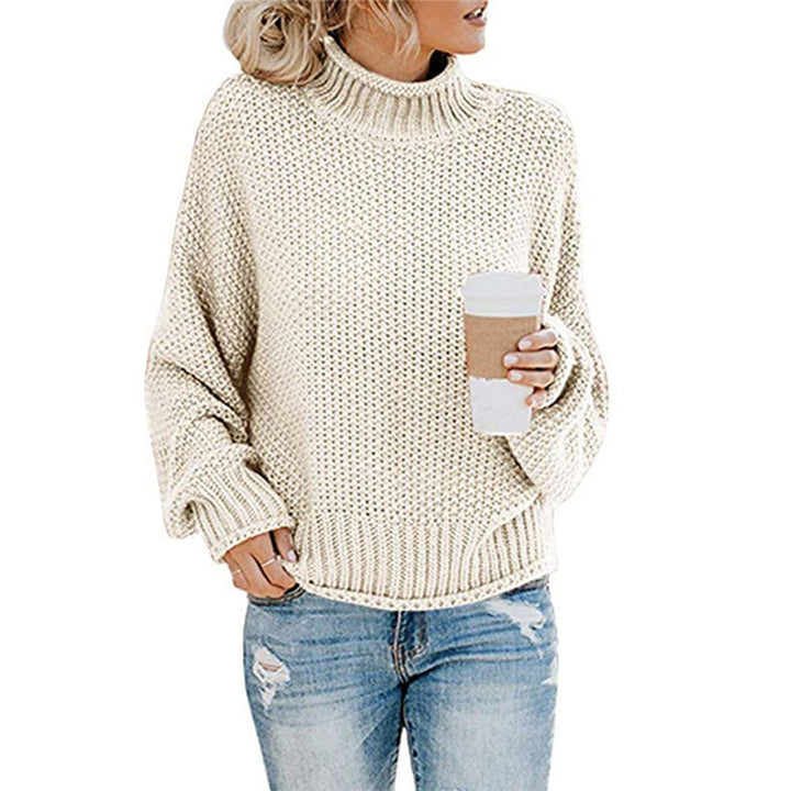 Vrouw in gebreide crèmekleurige trui met col, houdt een koffiebeker vast. Casual mode, herfstkleding, comfortabele damestrui.
