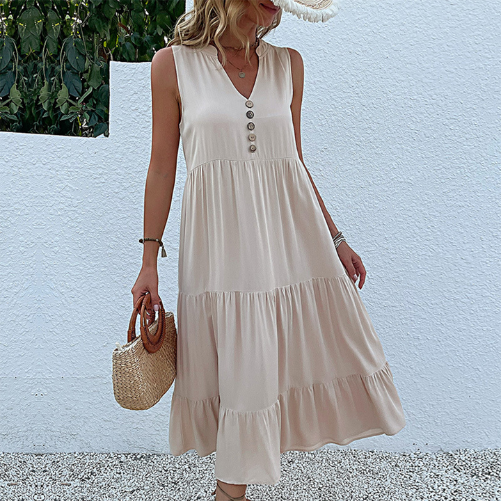 Vrouw in beige zomerjurk met knopen, draagt een strooien tas. Casual damesmode, perfecte outfit voor warme dagen. Stijlvolle en comfortabele look.