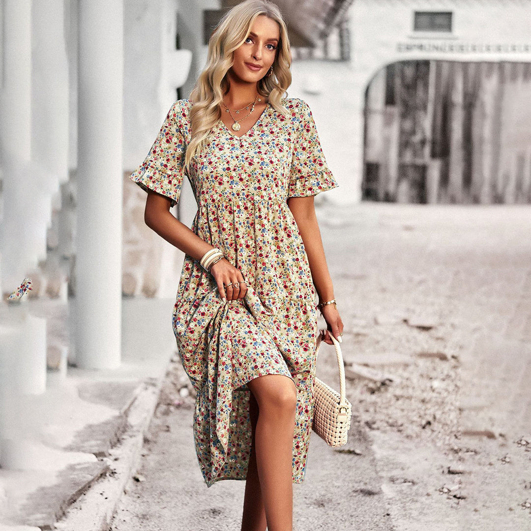 Blonde vrouw in bloemenjurk met rieten tas, wandelend op straat. Zomermode, casual dameskleding, bohemian stijl, buitenfotografie.