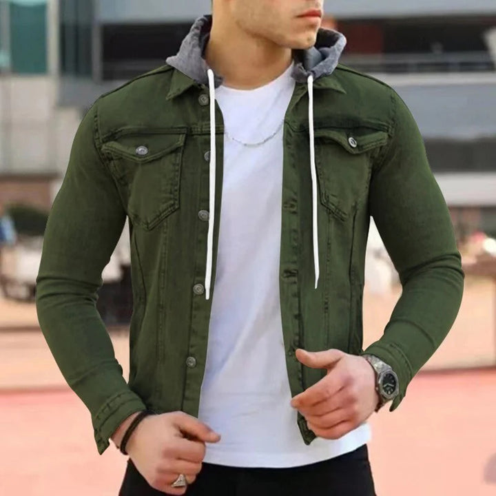 Man in legergroen jack met capuchon, witte T-shirt en zilveren ketting. Modieuze herenkleding, casual stijl, buitenomgeving.