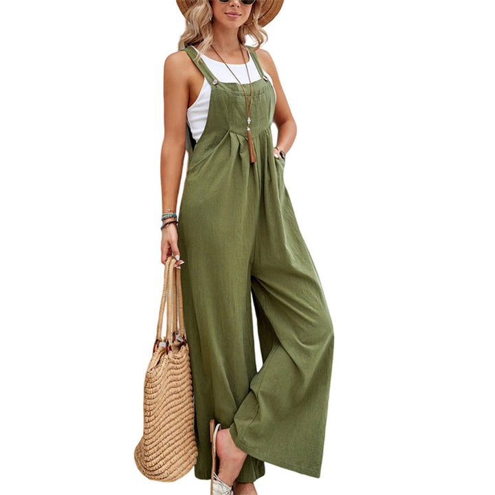 Vrouw in groene jumpsuit met wijde pijpen, witte top en strohoed, draagt een rieten tas. Trendy zomeroutfit, casual damesmode.
