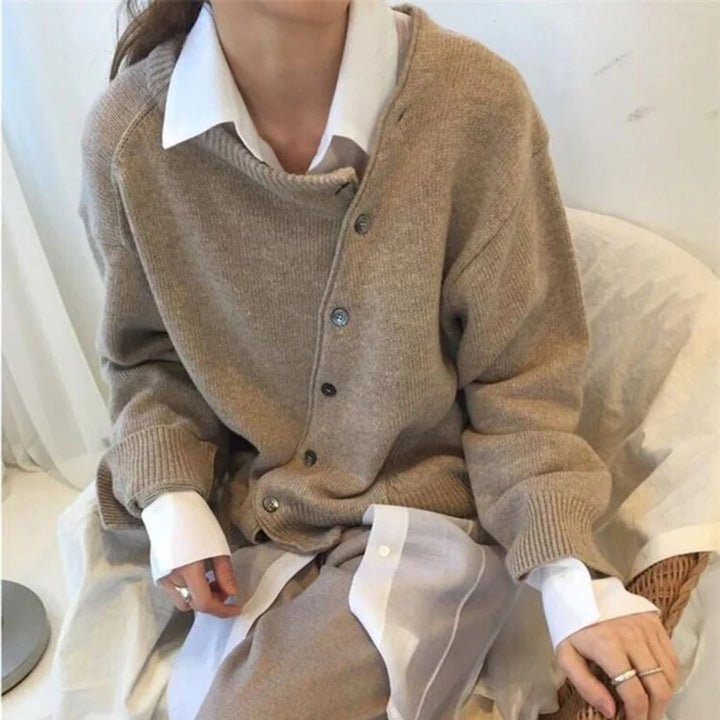 Vrouw draagt beige oversized gebreid vest met knopen over witte blouse. Modieuze herfstkleding, casual stijl, comfortabele damesmode.