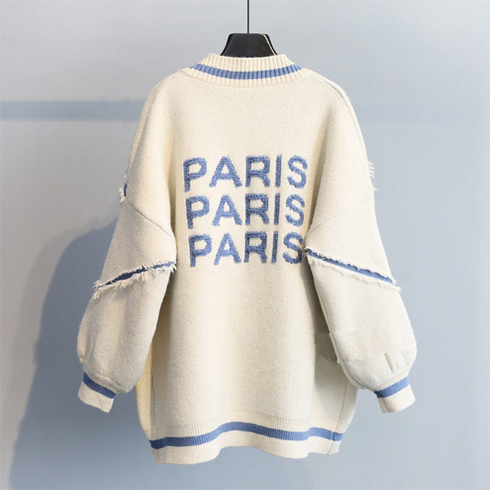Beige oversized trui met blauwe "PARIS" tekst, gerafelde details en ronde hals. Trendy damesmode, comfortabele casual stijl.