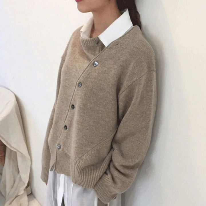 Beige damestrui met knopen, gedragen over een witte blouse. Stijlvolle casual outfit, ideaal voor herfstmode. Comfortabele en modieuze kleding.