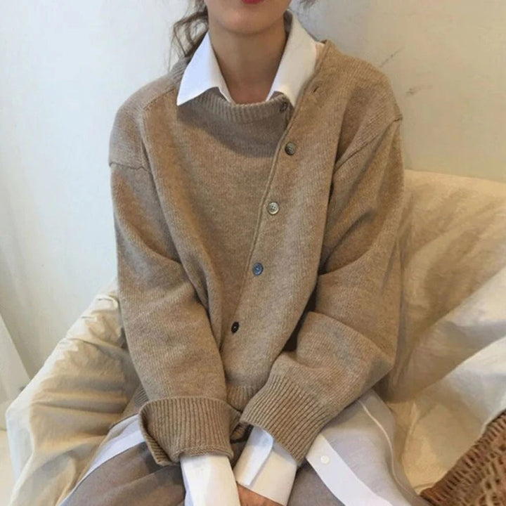 Beige oversized trui met knopen, gedragen over een witte blouse. Modieuze dameskleding, casual herfstoutfit, comfortabele stijl.