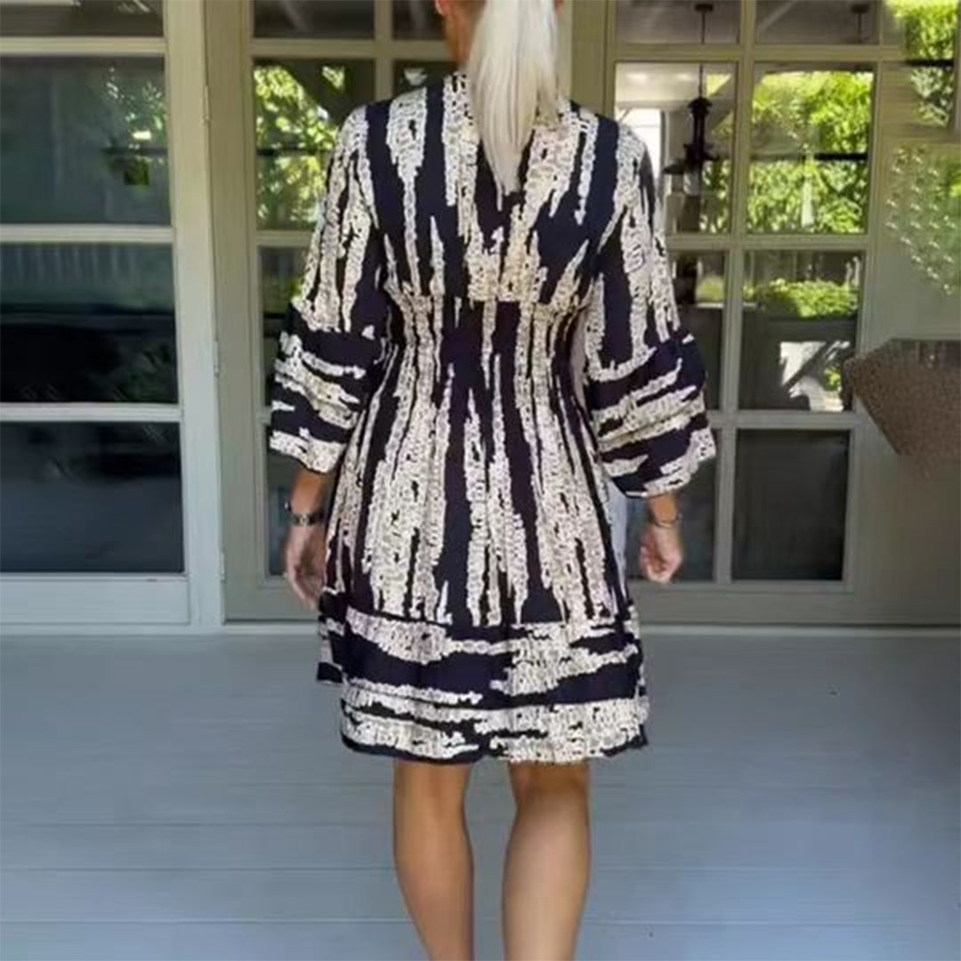 Vrouw in zwart-witte gestreepte jurk op veranda, zomermode, casual kleding, achteraanzicht, trendy dameskleding, comfortabele stijl.