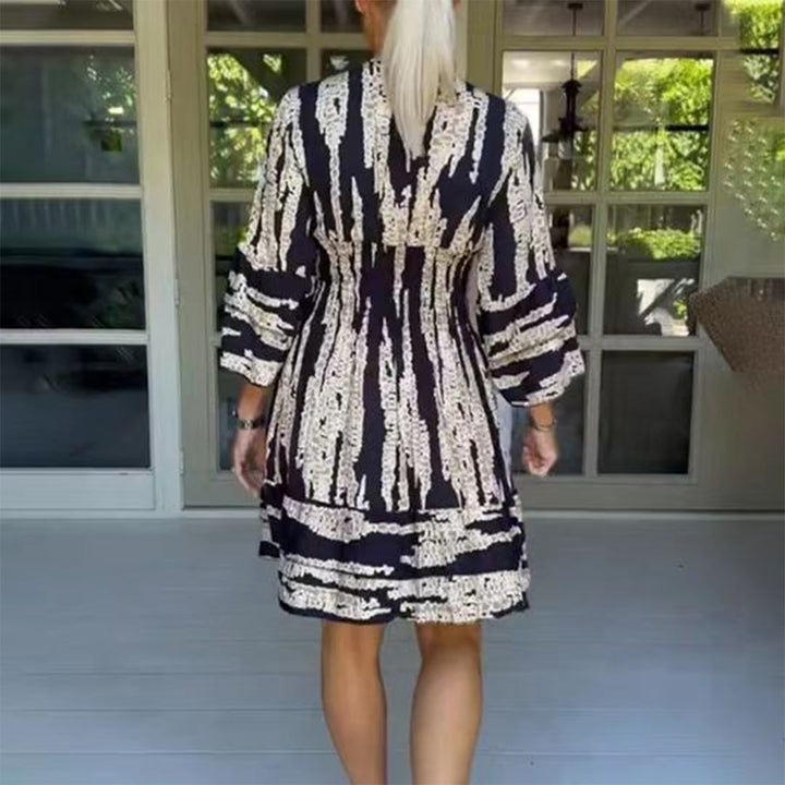 Vrouw in zwart-witte gestreepte jurk op veranda, zomermode, casual kleding, achteraanzicht, trendy dameskleding, comfortabele stijl.