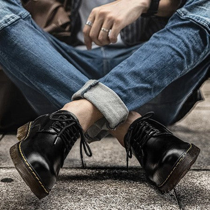 Zwarte leren veterlaarzen voor heren, gedragen met opgerolde jeans. Stijlvolle en duurzame schoenen, perfect voor casual en urban mode.