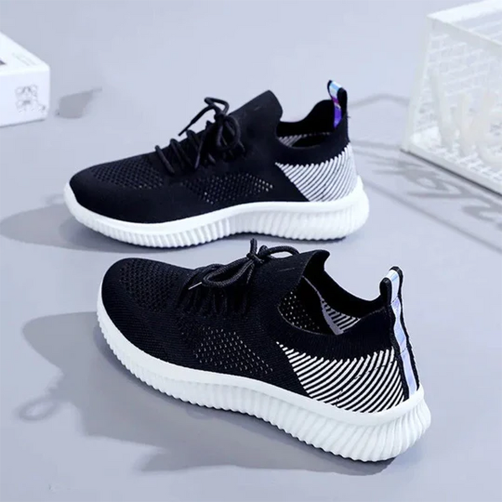 Zwarte sportschoenen met witte zool, ademend mesh bovenwerk, geschikt voor hardlopen en fitness. Stijlvol ontwerp, comfortabele pasvorm.