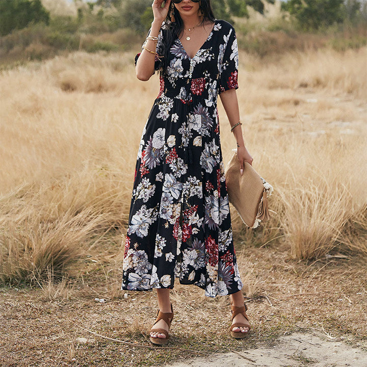 Vrouw in zwarte bloemenjurk met korte mouwen, staand in een veld. Zomerjurk, casual mode, bohemian stijl, elegante dameskleding.