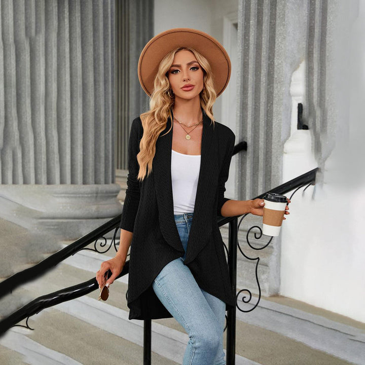 Vrouw in zwarte cardigan, witte top en jeans, met hoed en koffiebeker, poseert op trap. Mode, casual outfit, dameskleding, herfststijl.