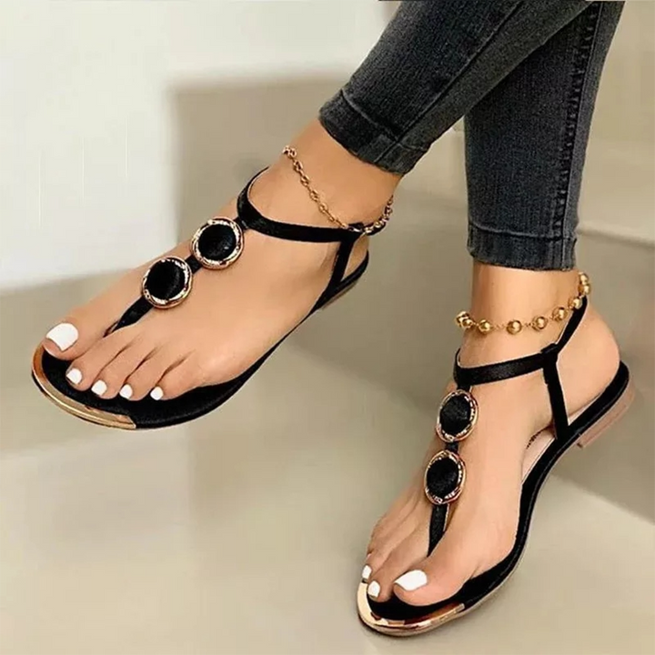 Zwarte damessandalen met gouden details en sieraden, gedragen met jeans. Stijlvolle zomerschoenen, perfect voor casual en elegante looks.