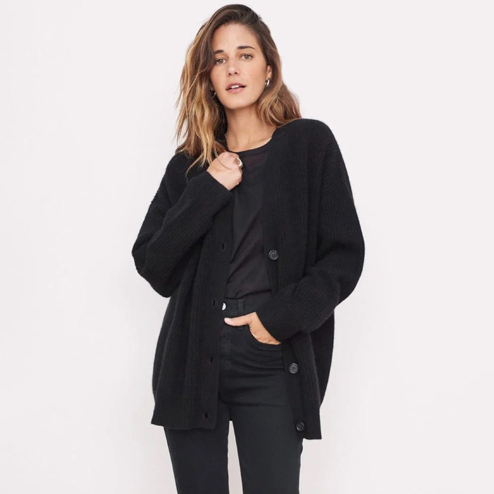 Vrouw draagt zwarte gebreide cardigan met knopen, casual mode, herfstkleding, stijlvolle damestrui, comfortabele outfit, minimalistisch design.