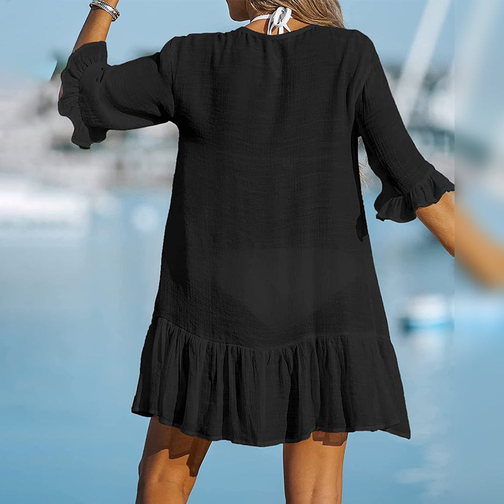 Zwarte strandjurk met ruches, driekwart mouwen en losse pasvorm, ideaal voor zomerse dagen. Perfecte strandkleding voor dames.