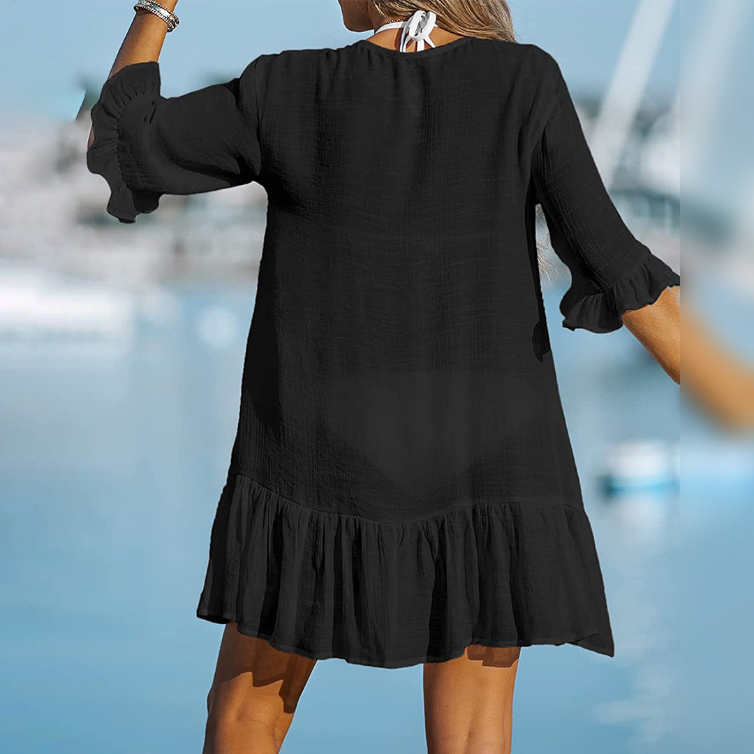 Zwarte strandjurk met ruches, driekwart mouwen en losse pasvorm, ideaal voor zomerse dagen. Perfecte strandkleding voor dames.