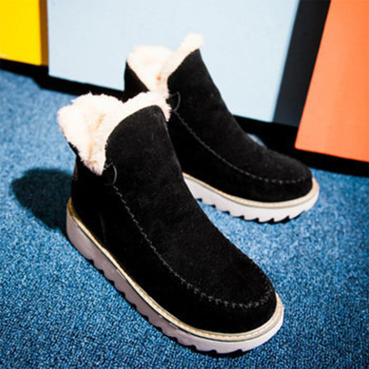 Zwarte suède laarzen met witte voering en dikke rubberen zool, perfect voor wintermode. Comfortabele en warme dameslaarzen op blauwe achtergrond.
