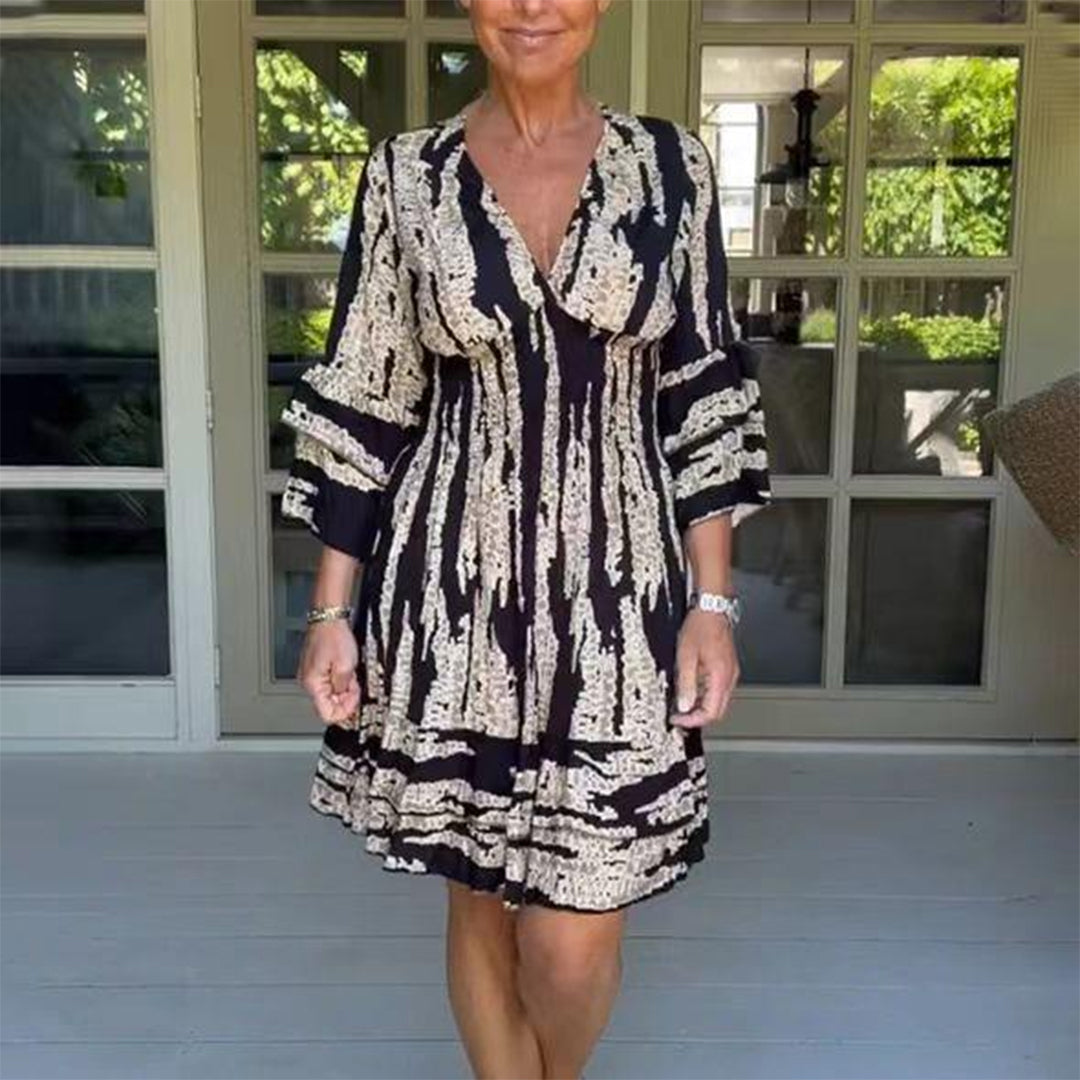 Vrouw in zwart-wit jurk met abstract patroon, staand op veranda. Modieuze dameskleding, zomerjurk, casual stijl, comfortabele pasvorm.