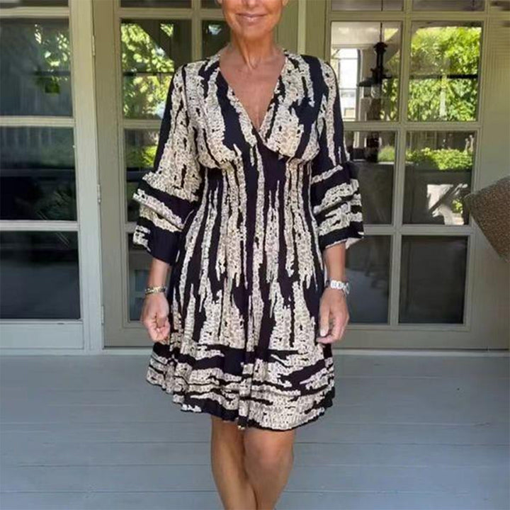 Vrouw in zwart-wit jurk met abstract patroon, staand op veranda. Modieuze dameskleding, zomerjurk, casual stijl, comfortabele pasvorm.