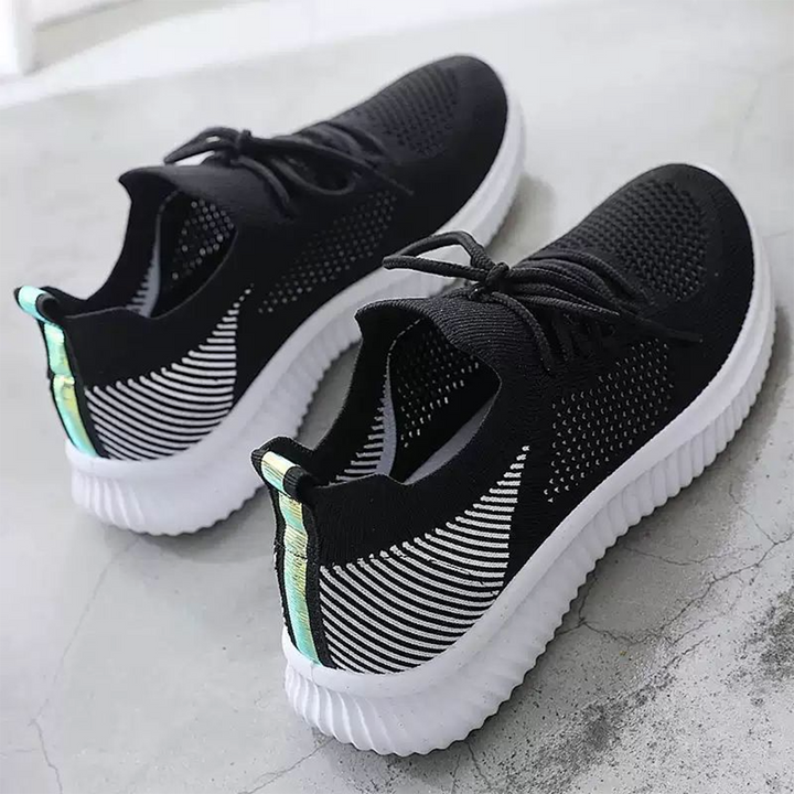 Zwarte sportschoenen met witte zool, ademend mesh bovenwerk en reflecterende details. Perfect voor hardlopen en casual gebruik. Unisex design.