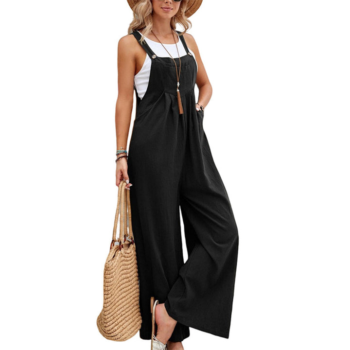 Vrouw in zwarte jumpsuit met witte top, strohoed en rieten tas. Modieuze zomeroutfit, casual stijl, dameskleding.