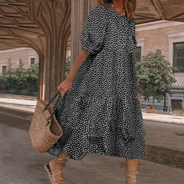 Vrouw in zwarte jurk met witte stippen, draagt een rieten tas. Zomerse outfit, casual stijl, stedelijke achtergrond. Perfect voor warme dagen.