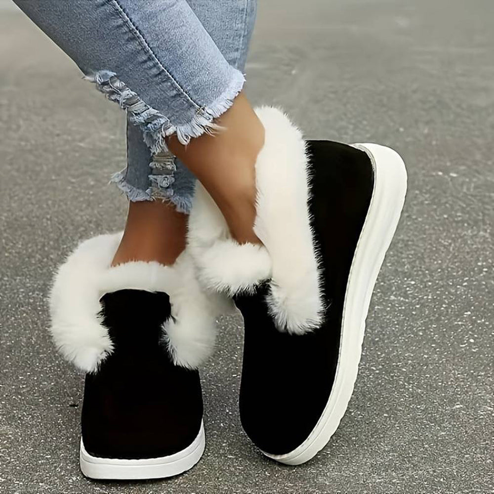 Zwarte winterlaarzen met witte bontvoering, gedragen met gescheurde jeans. Warme dameslaarzen, comfortabele wintermode, trendy schoeisel.