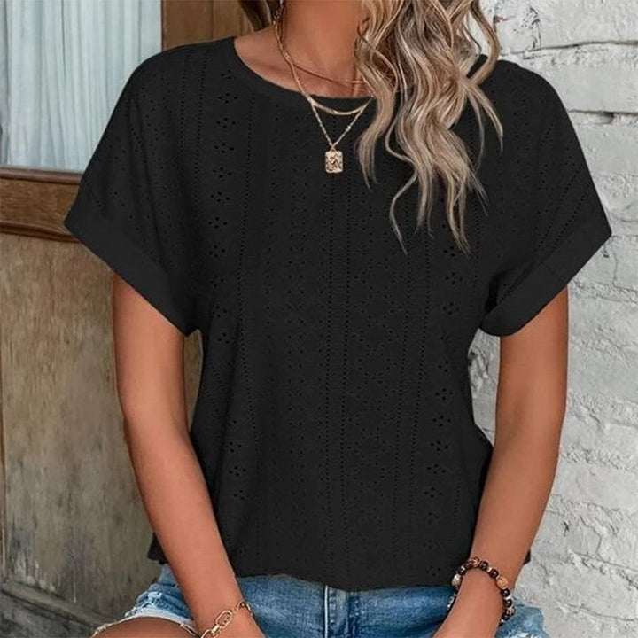 Vrouw draagt zwarte geperforeerde blouse, korte mouwen, casual stijl, gecombineerd met denim shorts. Perfect voor zomerse mode en casual outfits.