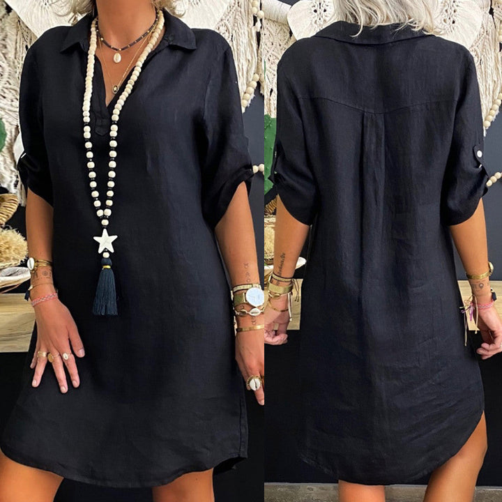 Zwarte linnen jurk met opgerolde mouwen en knoopsluiting, gedragen door model. Boho-stijl, casual zomeroutfit, perfect voor strand of vakantie.