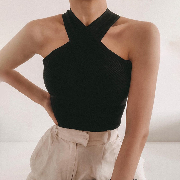 Zwarte haltertop met gekruiste bandjes, gedragen door een model. Stijlvolle damesmode, perfect voor casual en formele gelegenheden.