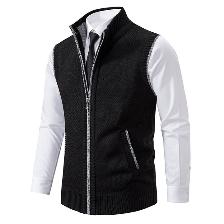 Zwarte herenvest met ritssluiting, gedragen over een witte overhemd en stropdas. Stijlvolle, casual outfit voor herenmode.