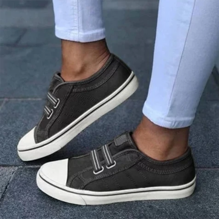 Zwarte canvas sneakers met witte zolen en elastische veters, gedragen door persoon in lichtblauwe jeans. Casual schoenen voor dagelijks gebruik.