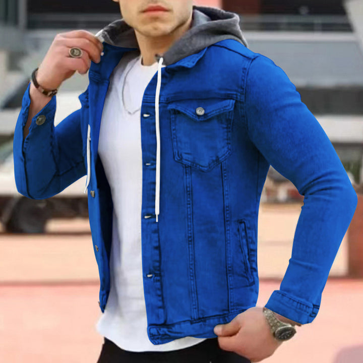Man in blauwe spijkerjas met capuchon, witte t-shirt, en zwarte broek. Modieuze herenkleding, casual streetwear, denim jack.