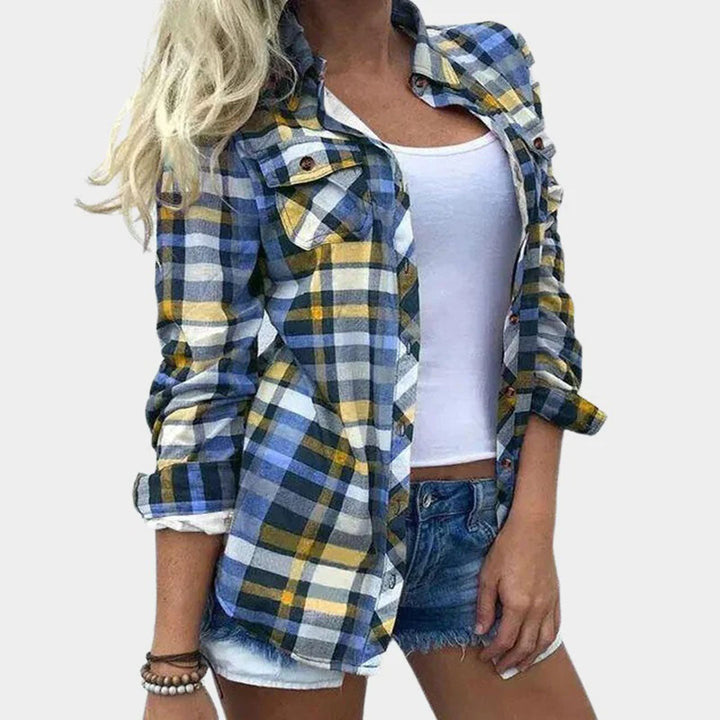 Vrouw in blauw-geel geruite blouse, witte tanktop en denim shorts. Modieuze casual dameskleding, zomerse outfit, trendy stijl.
