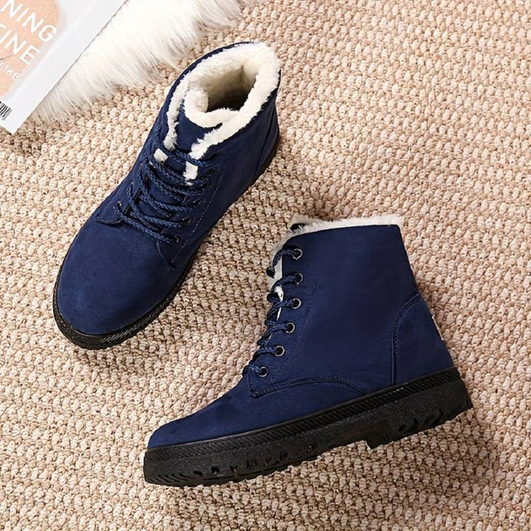 Blauwe winterlaarzen met warme voering, stevige zool en veters op beige tapijt. Perfect voor koude seizoenen. Comfortabele en modieuze schoenen.