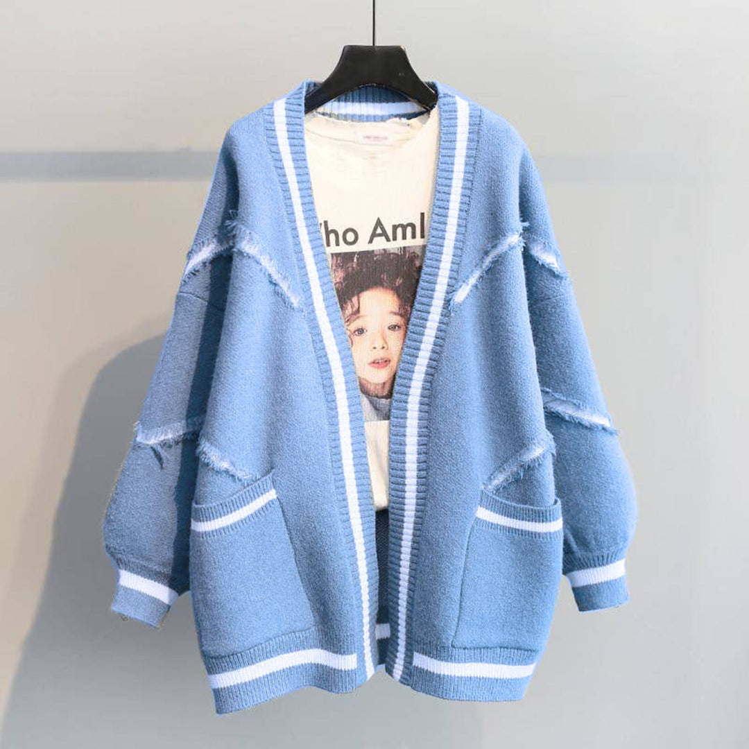Blauwe oversized gebreide cardigan met witte strepen en zakken, hangend aan een hanger. Perfect voor casual mode en herfstoutfits.